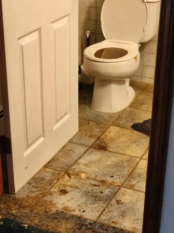 Sewage backup from a toilet spread across a bathroom floor