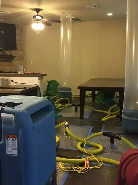 Drying equipment and yellow hoses stand among furniture beneath a ceiling fan