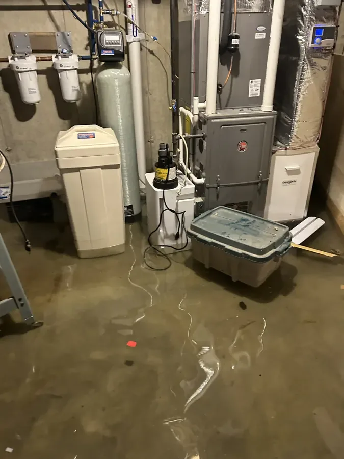 Standing water covers a basement utility room floor around heating and water equipment