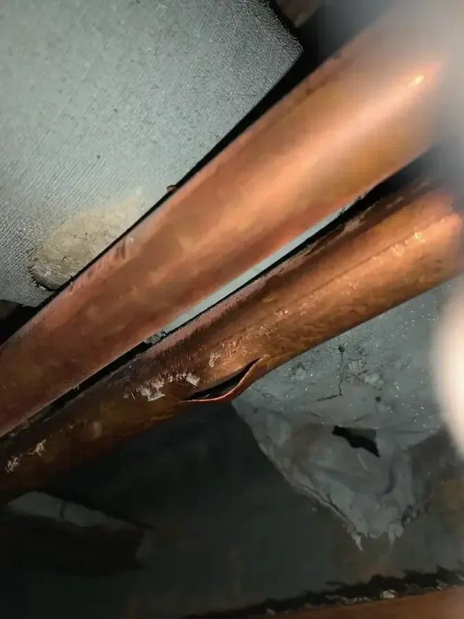 A close view shows a split in a copper pipe beside another copper pipe