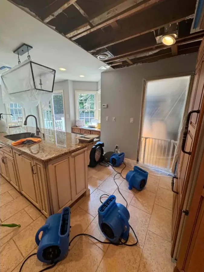 Air movers drying a kitchen floor under an opened ceiling